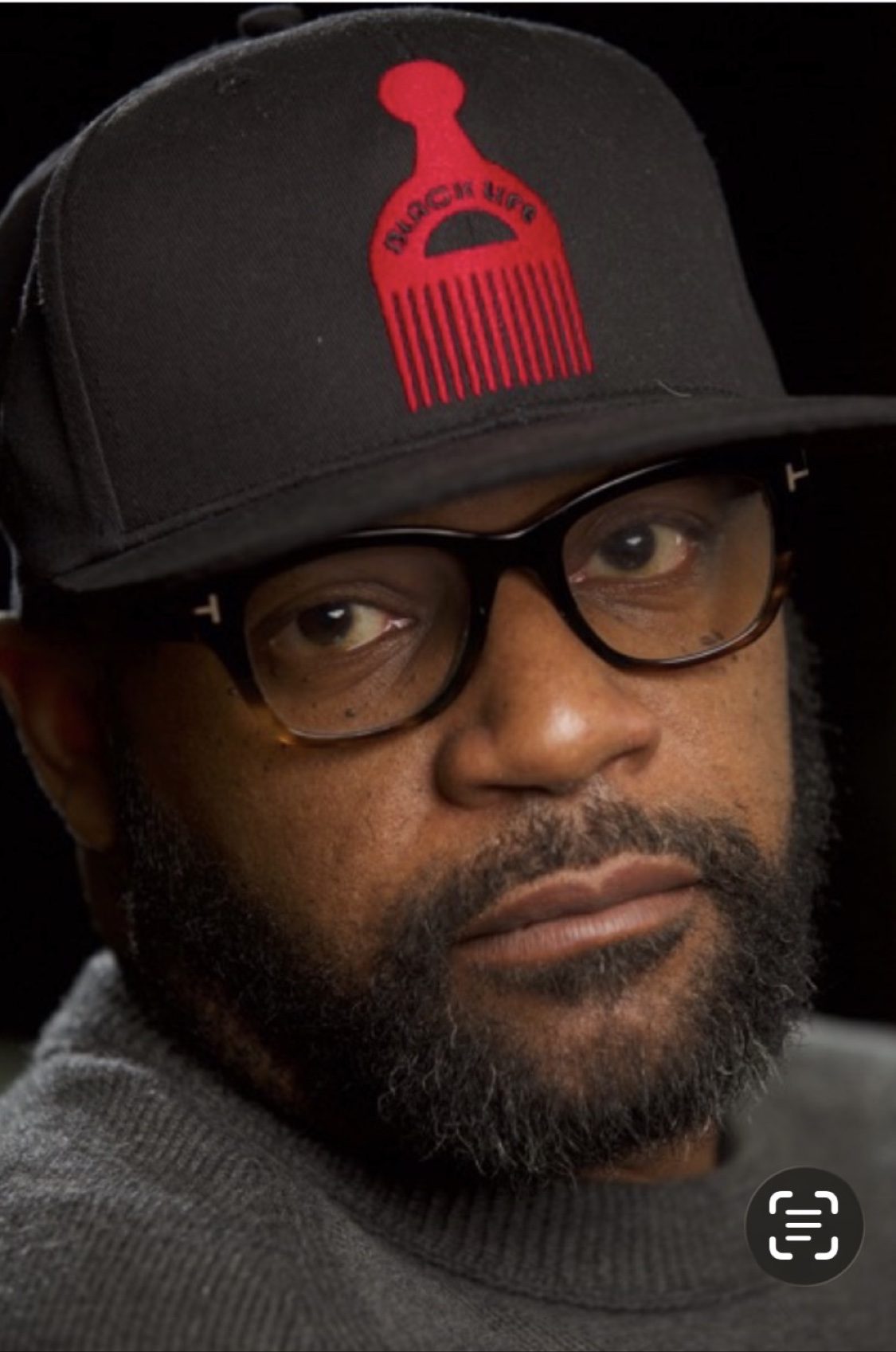 Siddiq in a black cap with red afro pick logo and glasses
